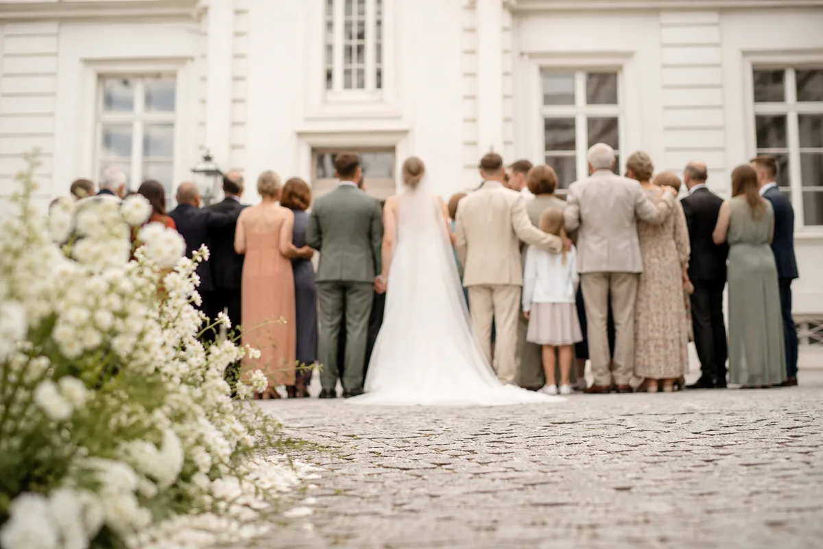 Groupe familial rassemblé devant une façade claire pour une photo de mariage